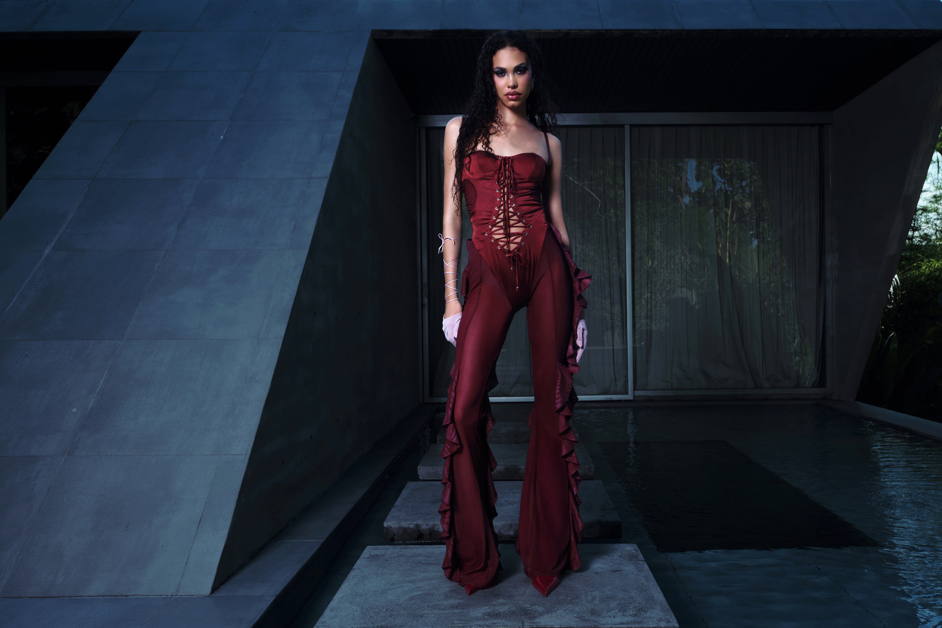 Woman in a red jumpsuit standing in a modern architectural setting